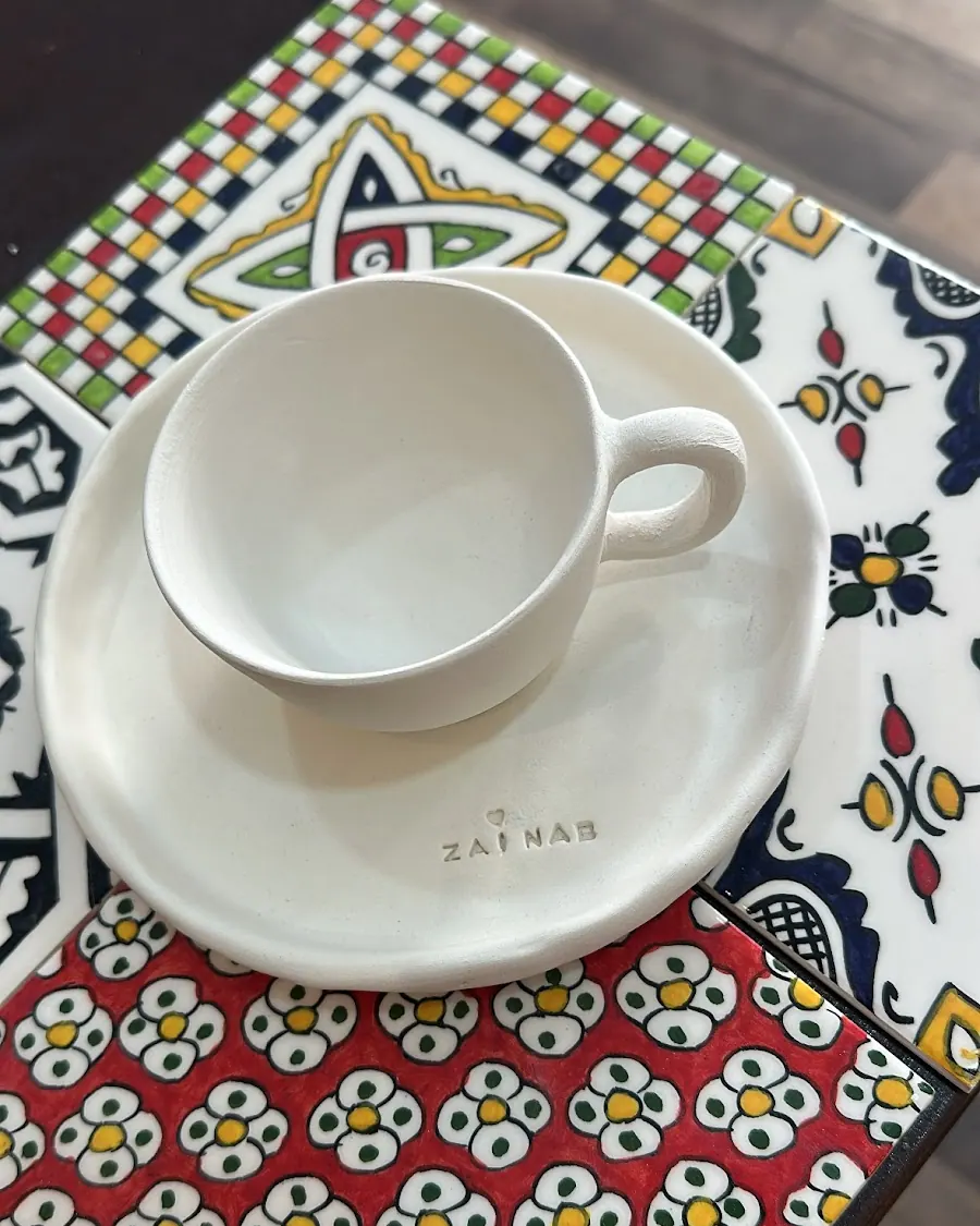 Tasse et soucoupe blanches marquées d'un prénom, sur du zellige