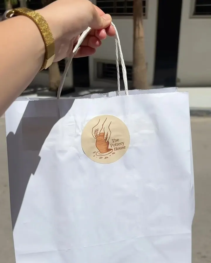 Les pièces terminées remises dans un sac blanc au logo de l'atelier