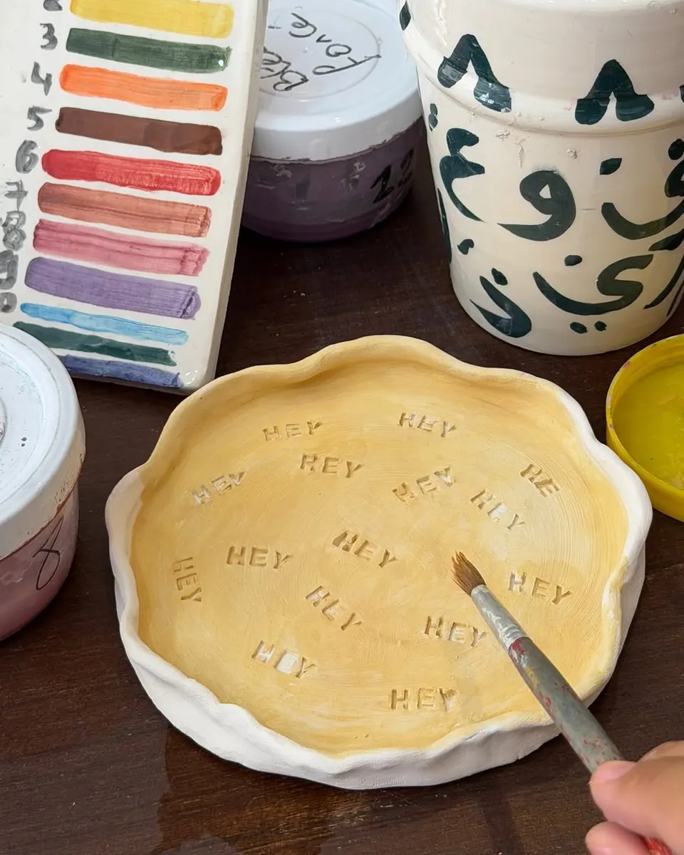 Un pinceau colore une assiette jaune aux bords ondulés
