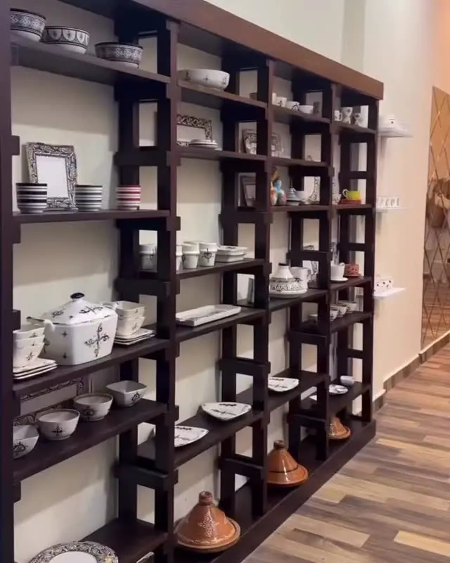 Étagères en bois sombre chargées de céramiques le long de l'atelier